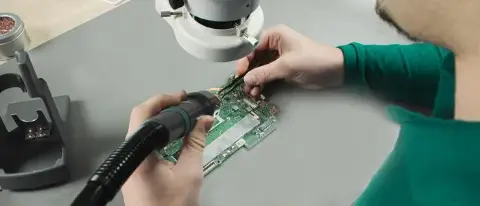 Cursist soldeert met hot air aan een printplaat onder de microscoop